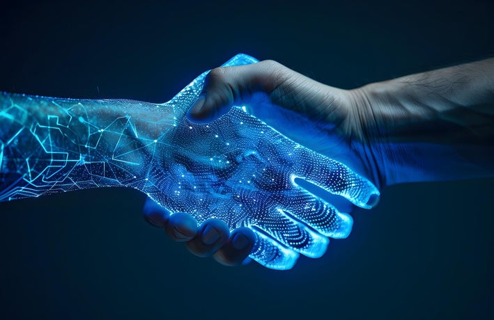 A human and an AI robot shaking hands.