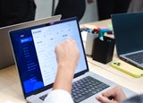 A person pointing at software on a laptop screen