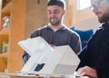 Two men standing behind and using a white POS system, including a white terminal and printer