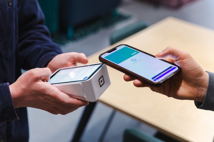 A close-up of someone taking a card payment with a Square card machine terminal