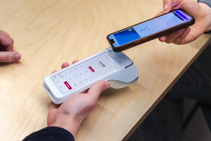 A close-up of someone taking a card payment with a white Take Payments Plus card reader